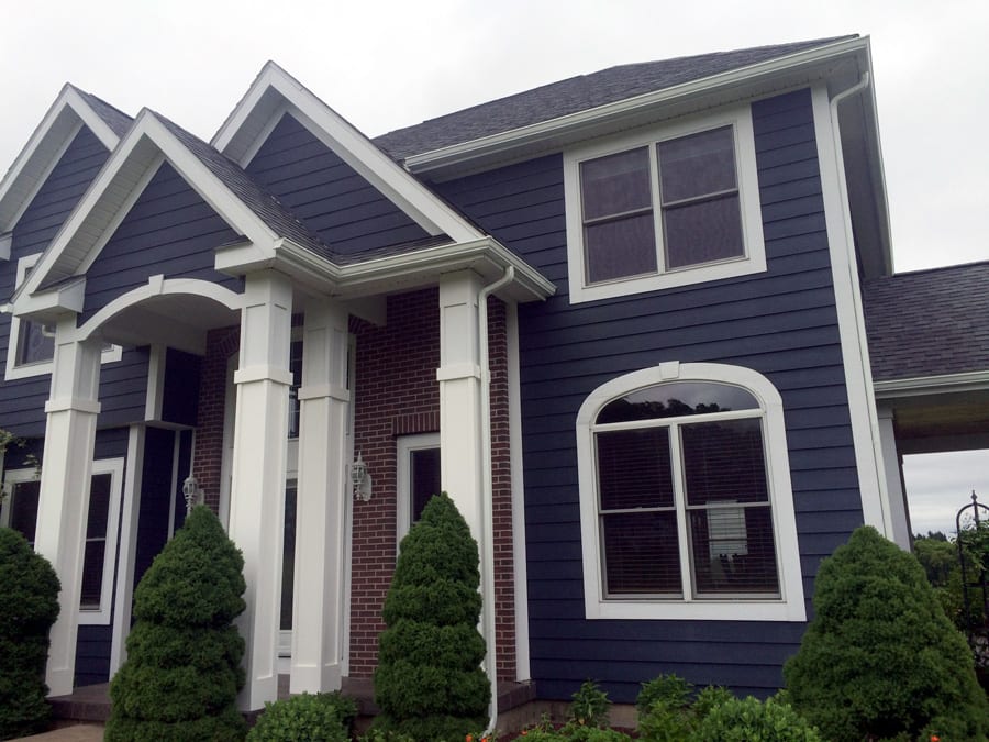 Navy home with white eavestroughs and roofing completed